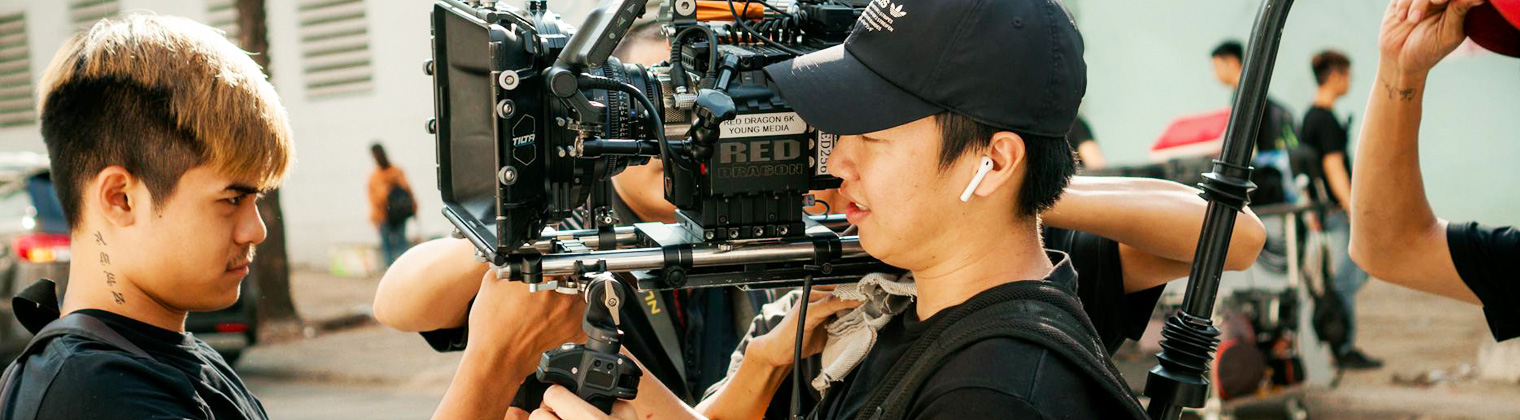 Image of a cameraman checking out the camera on the shoulder of the camera operator to make a technical video